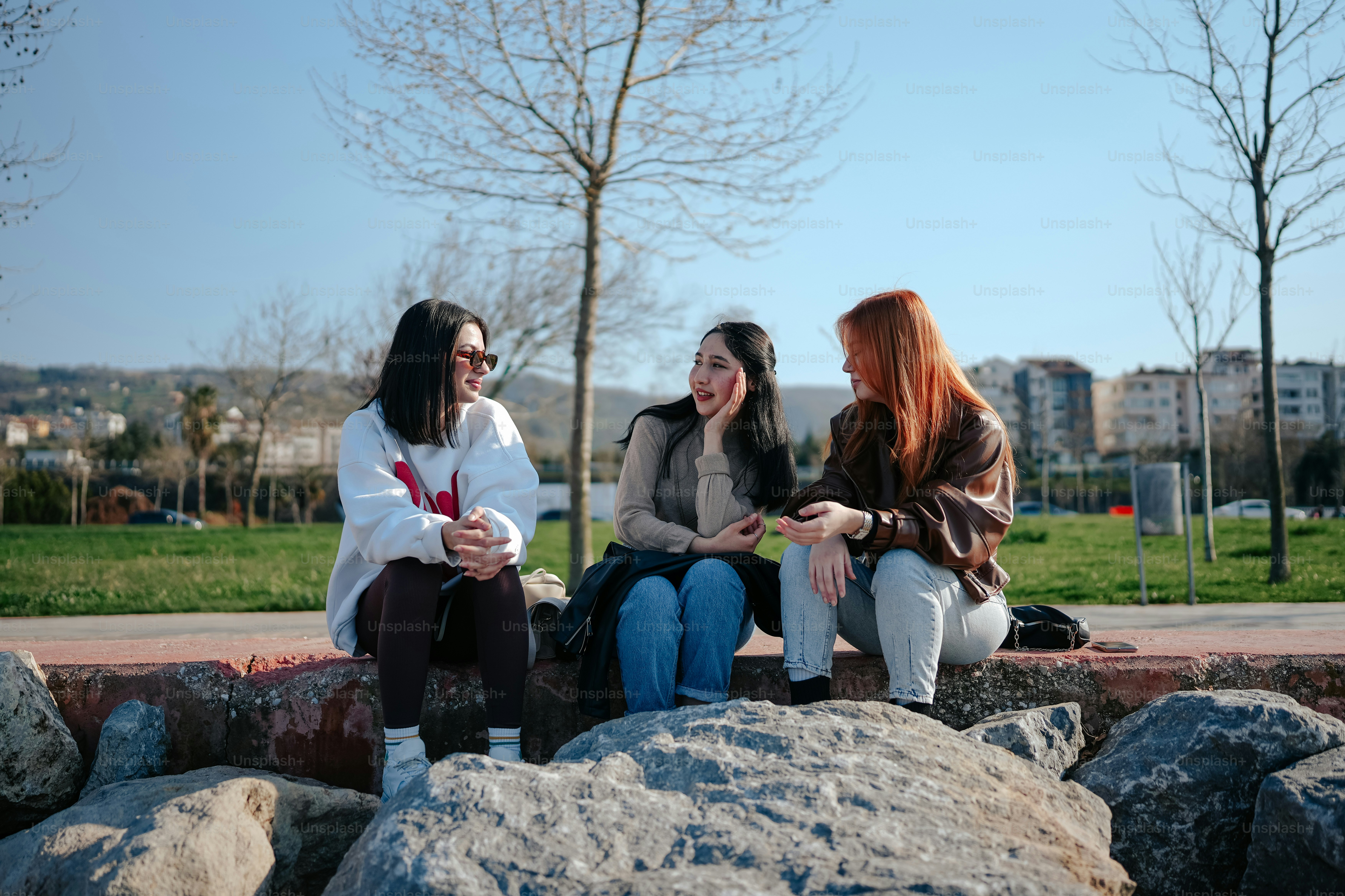 Tres mujeres sentadas en una roca hablando entre sí