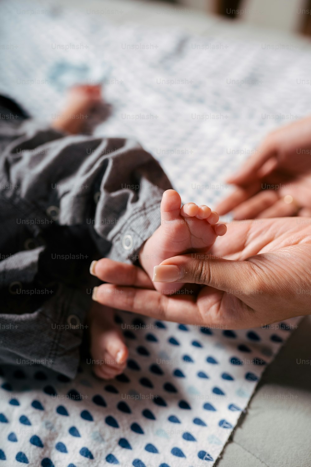 a person holding a baby's hand on top of a bed