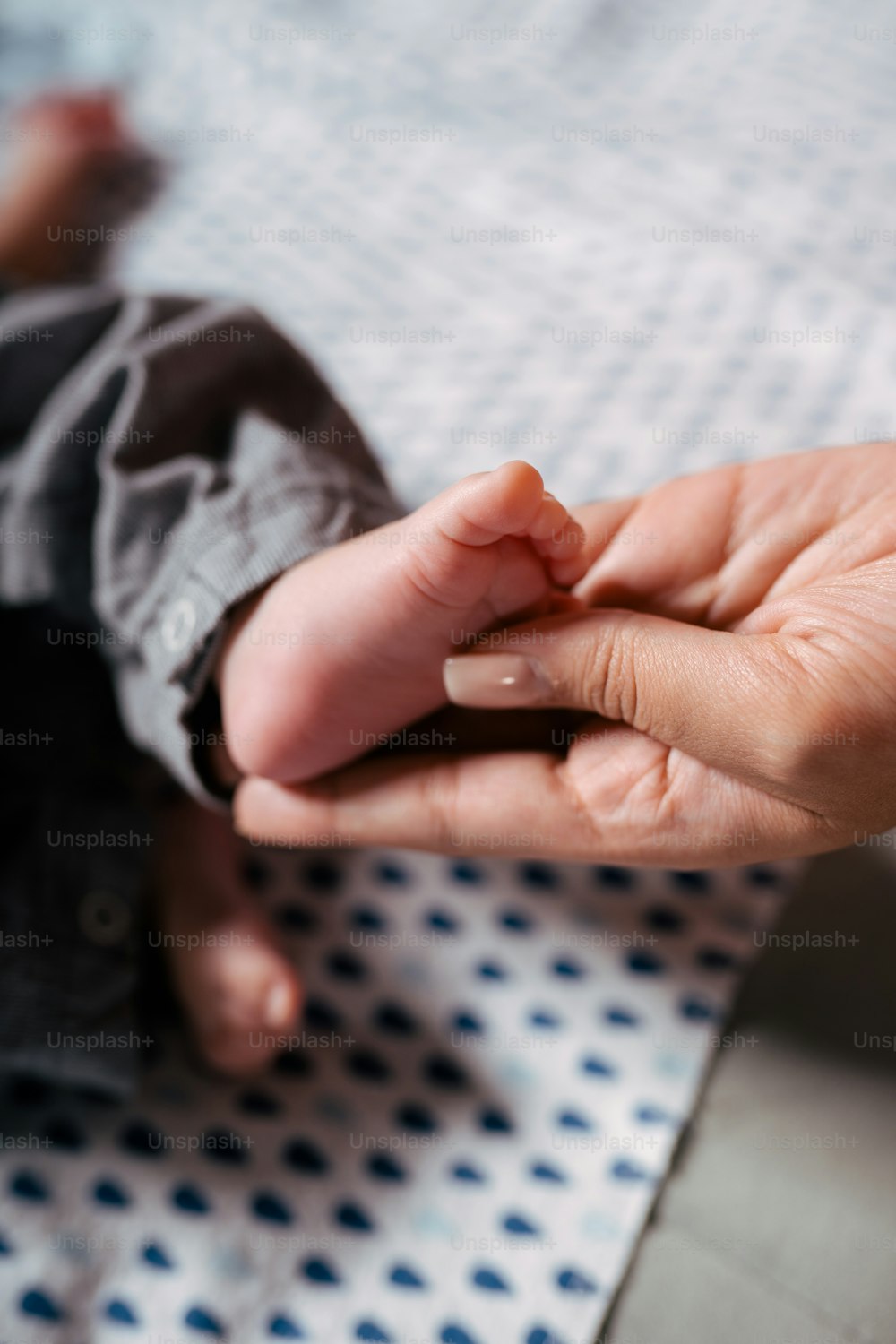 a person holding a baby's hand on top of a bed