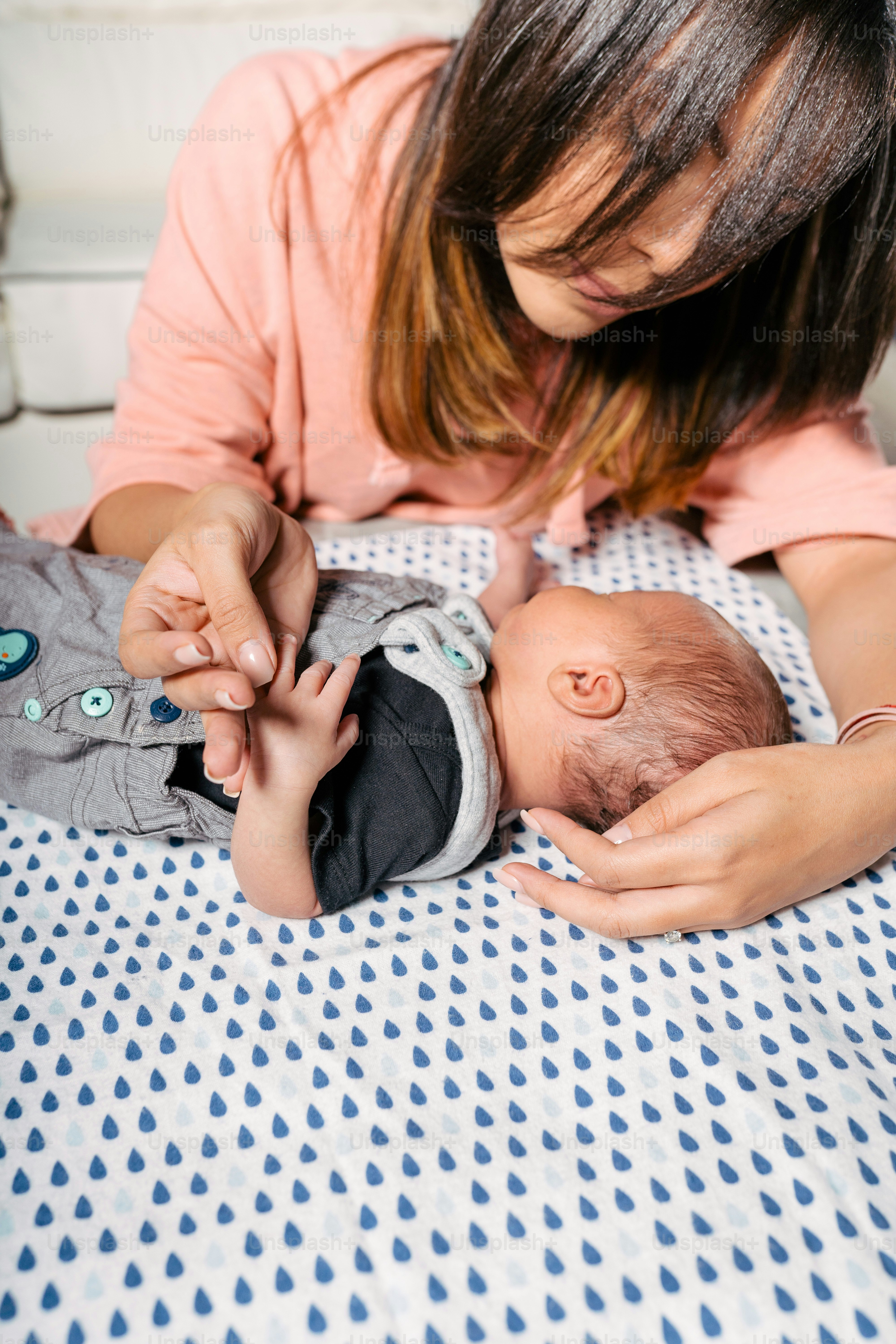 Une femme tient un bébé sur un lit