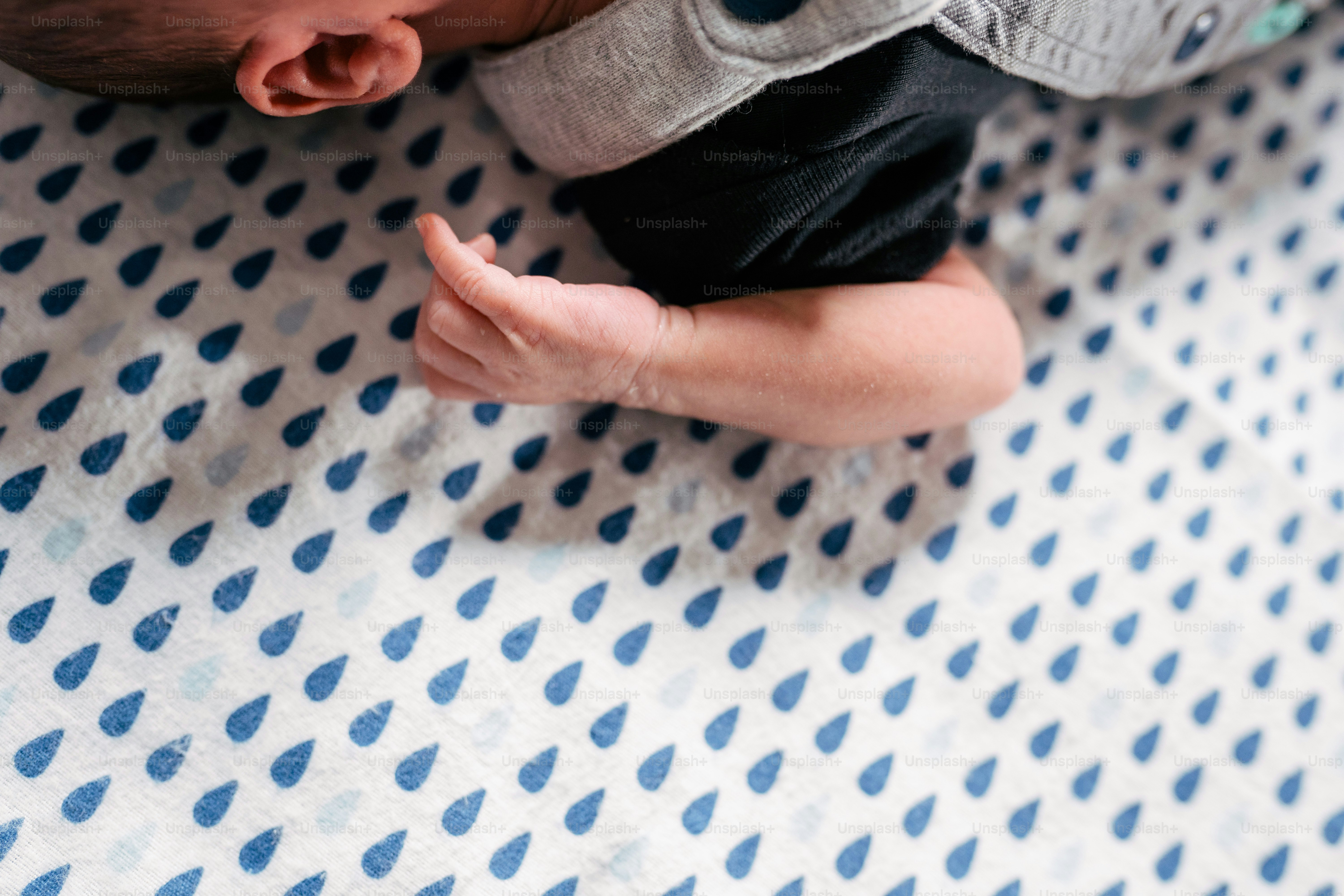 a baby laying on top of a blue and white blanket