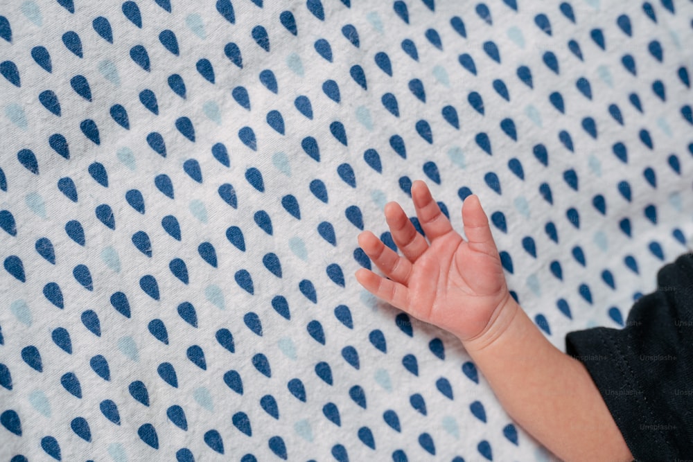 a baby's hand on a blue and white blanket