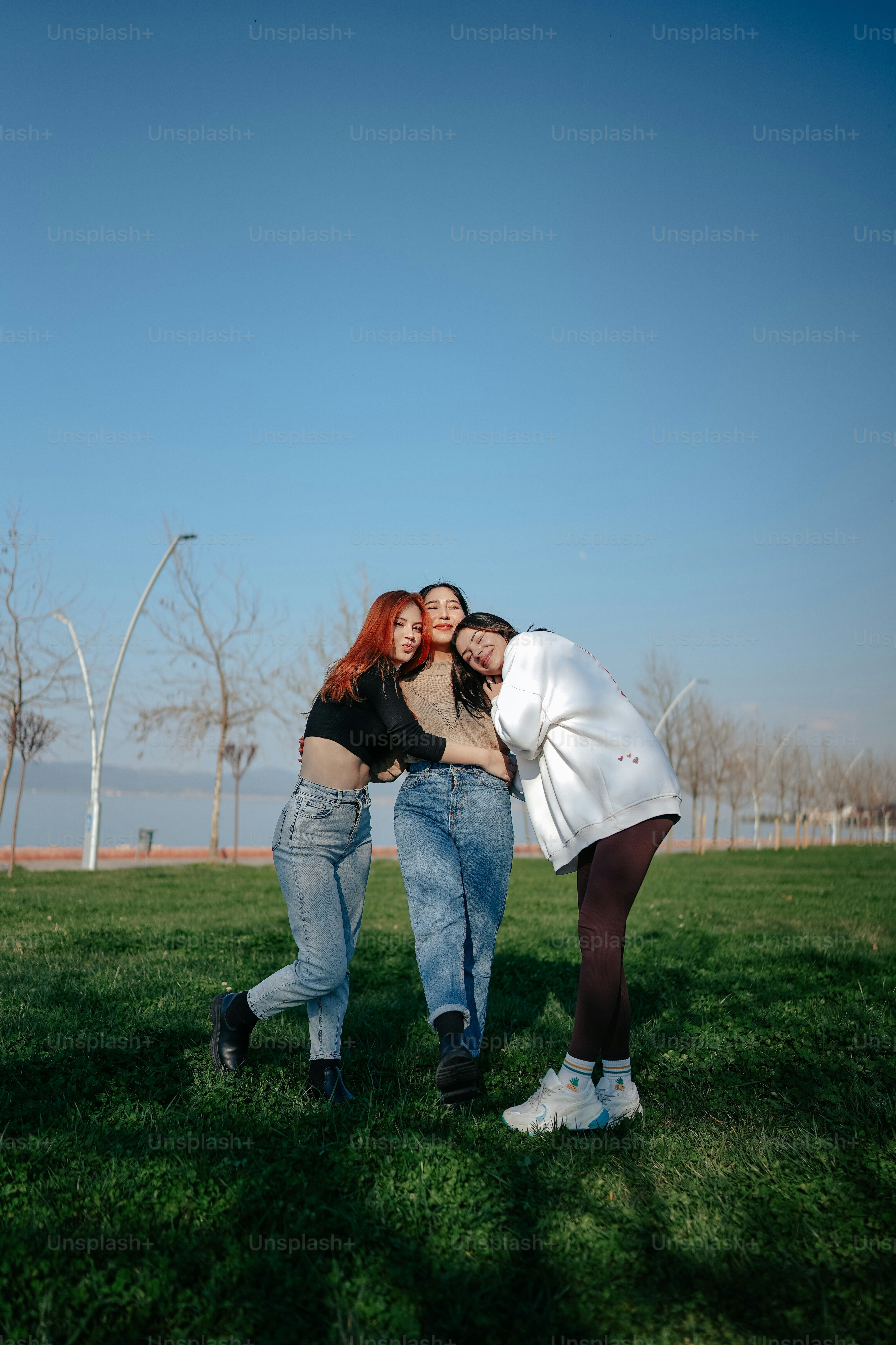 A group of three women standing next to each other on a field photo ...