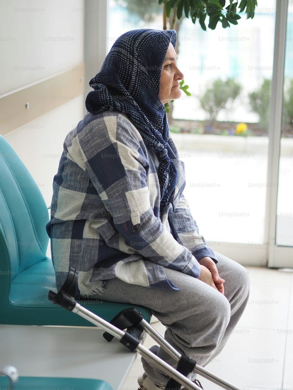 a woman sitting in a waiting room with her luggage