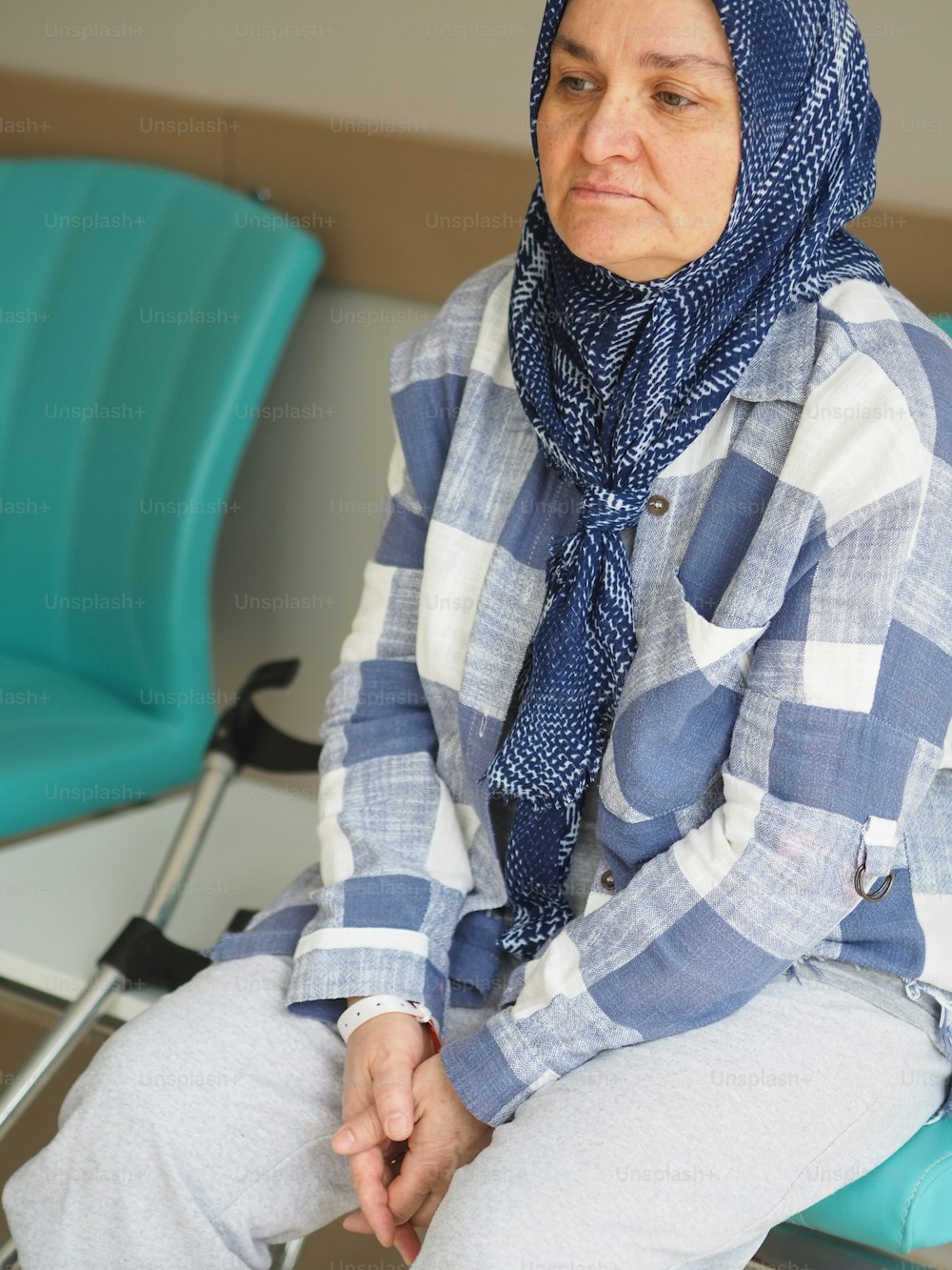 a woman sitting in a chair wearing a blue scarf