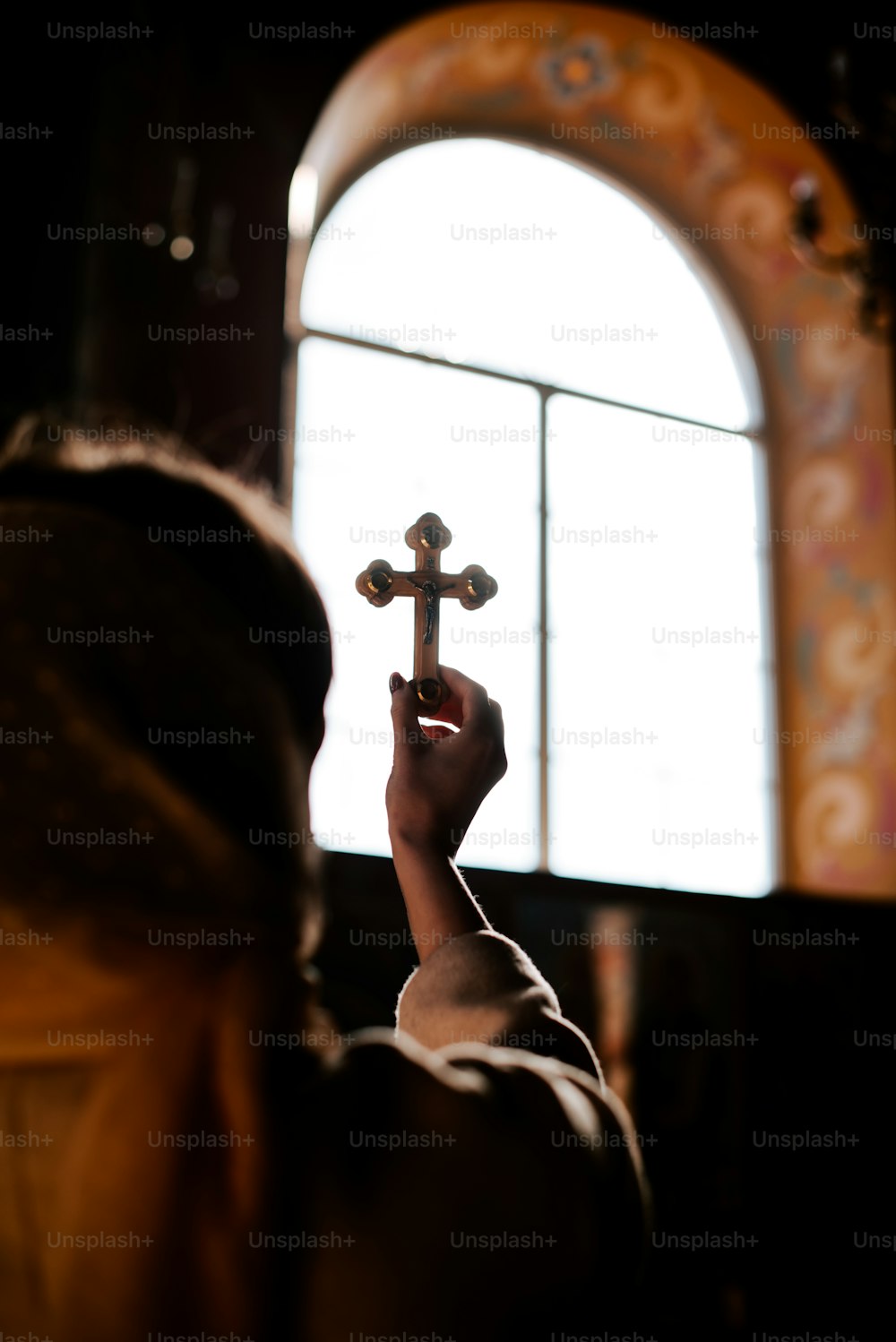 a woman holding a cross in front of a window