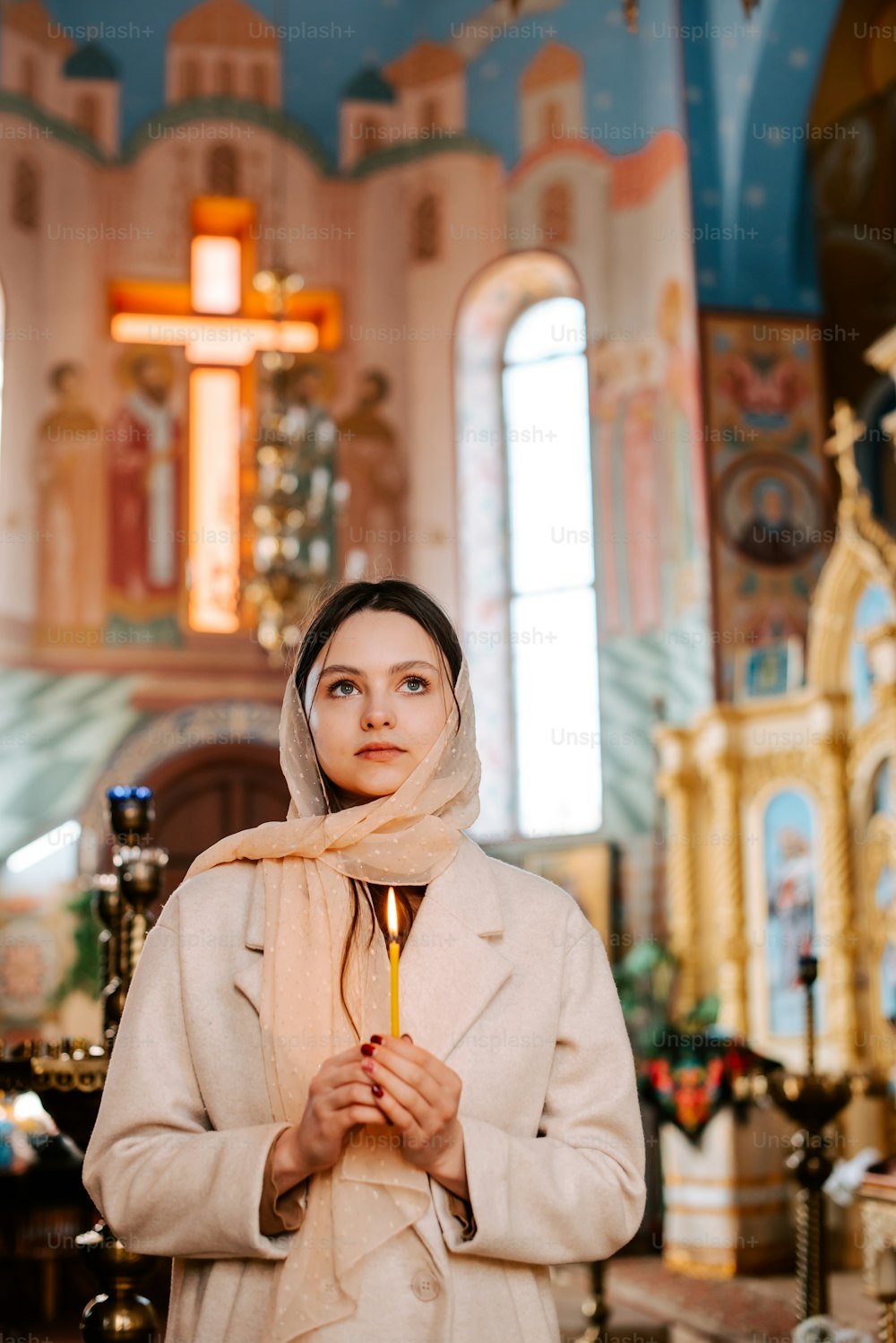 a woman standing in a church holding a candle