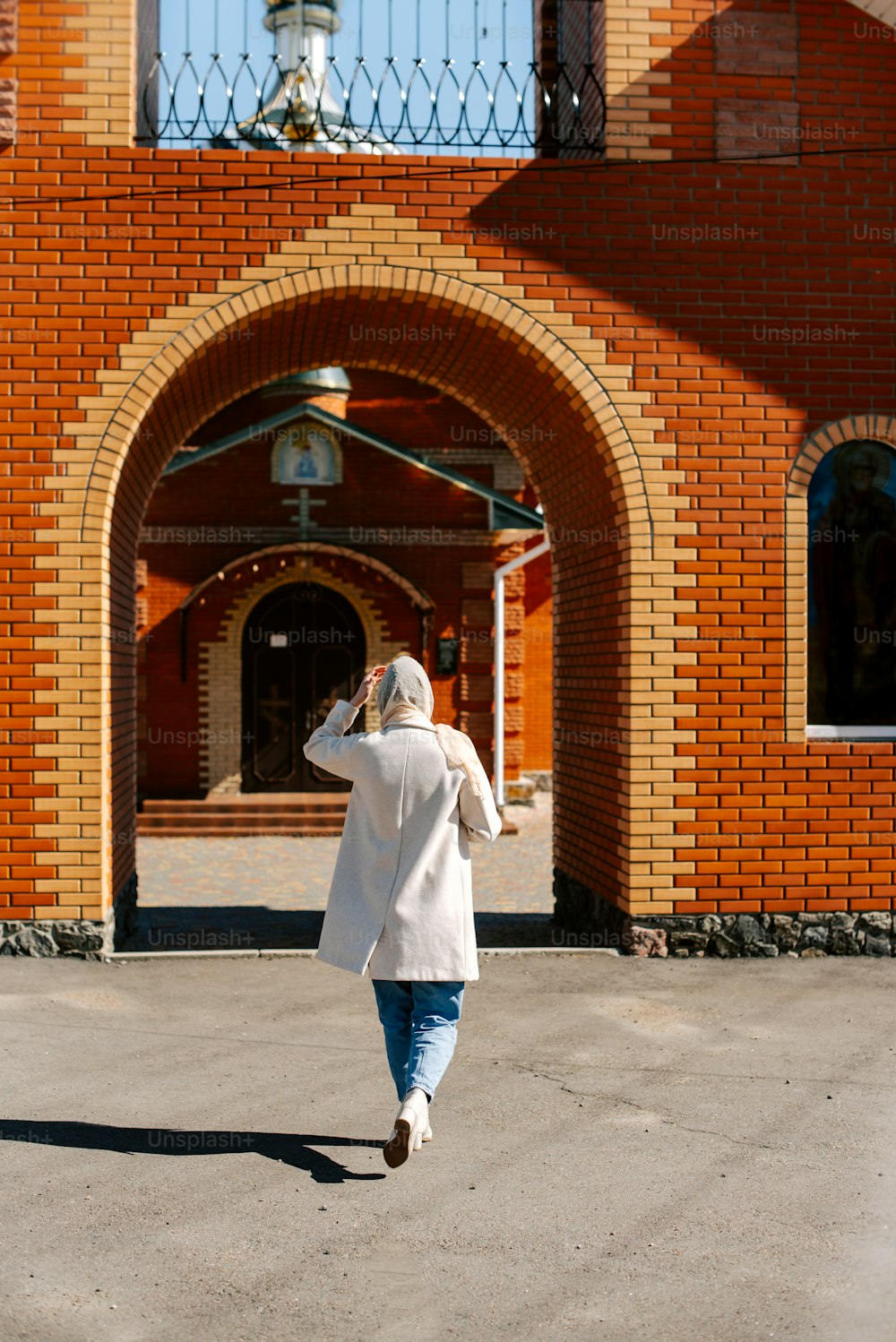 Une femme marchant devant un bâtiment en briques