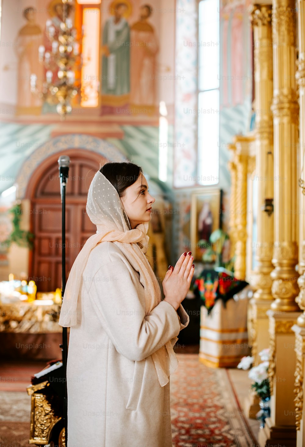 a woman standing in a church holding her hands together