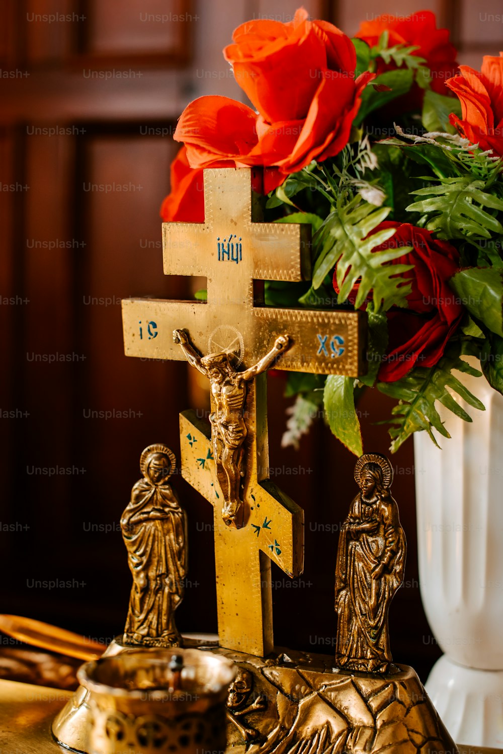 a cross with a crucifix and flowers in a vase