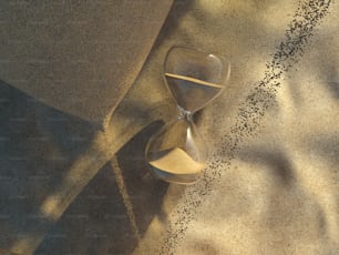 an hourglass sitting on top of a sand covered ground