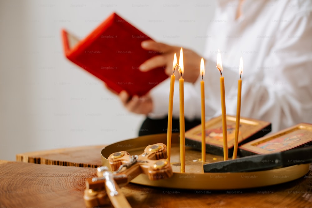 a person holding a red book in front of some candles