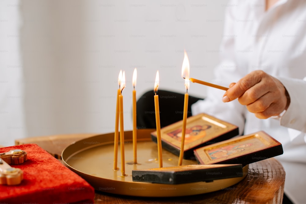 a person lighting candles on a tray on a table
