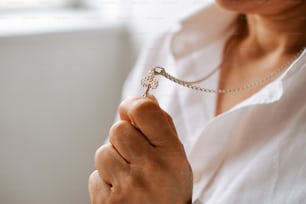 Una mujer con una camisa blanca sosteniendo un collar de plata