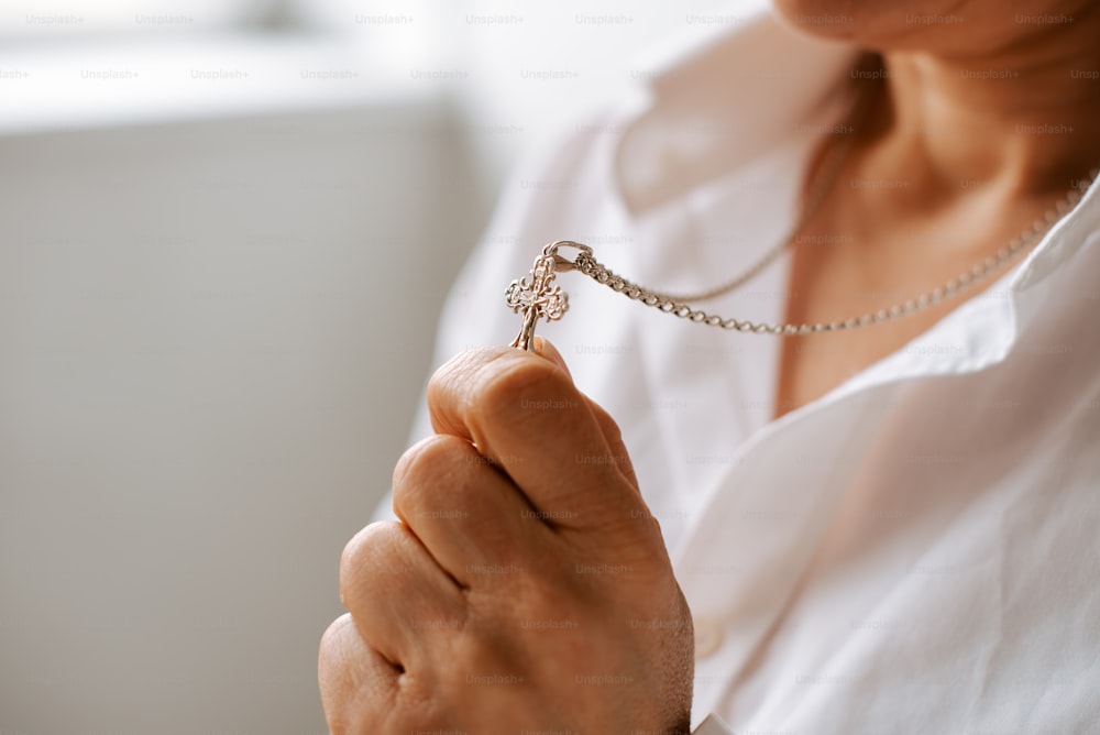 a woman wearing a white shirt holding a silver necklace