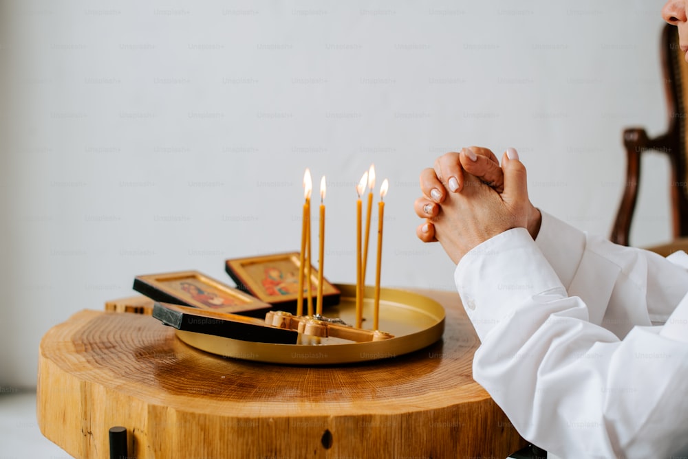 a person sitting at a table with a tray of candles