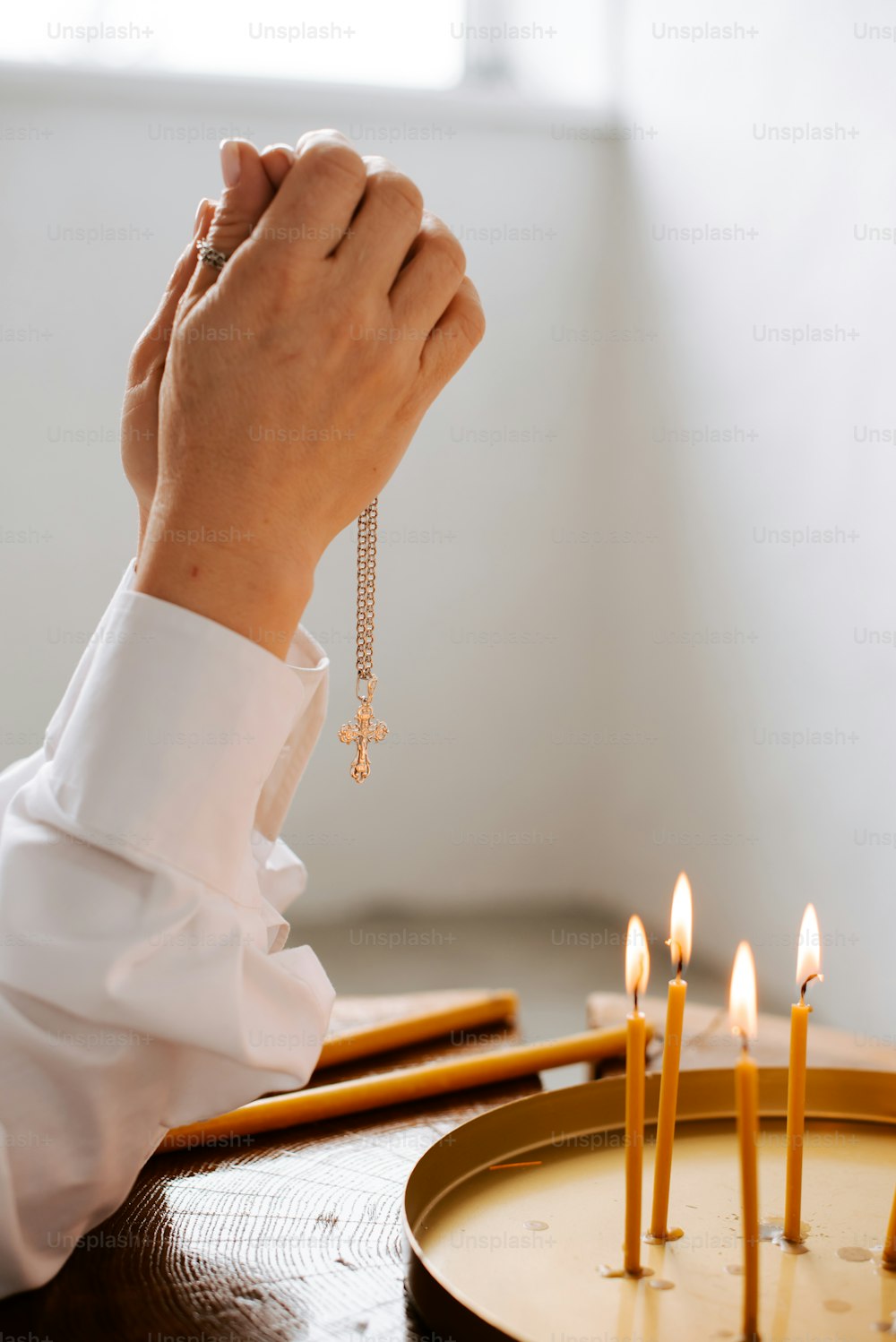 a person holding a rosary in front of a cake with candles