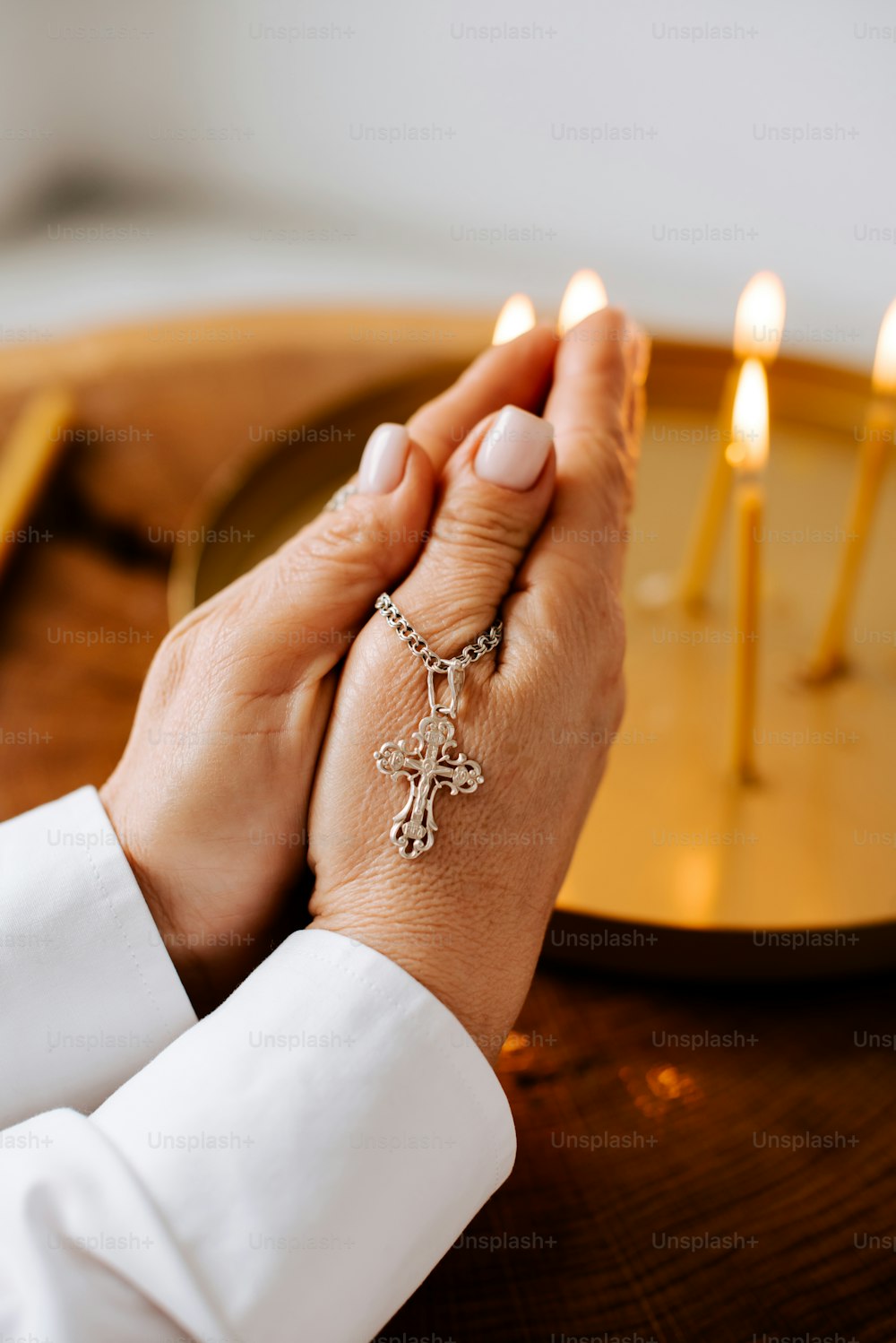 uma mulher segurando as mãos na frente de um prato com velas