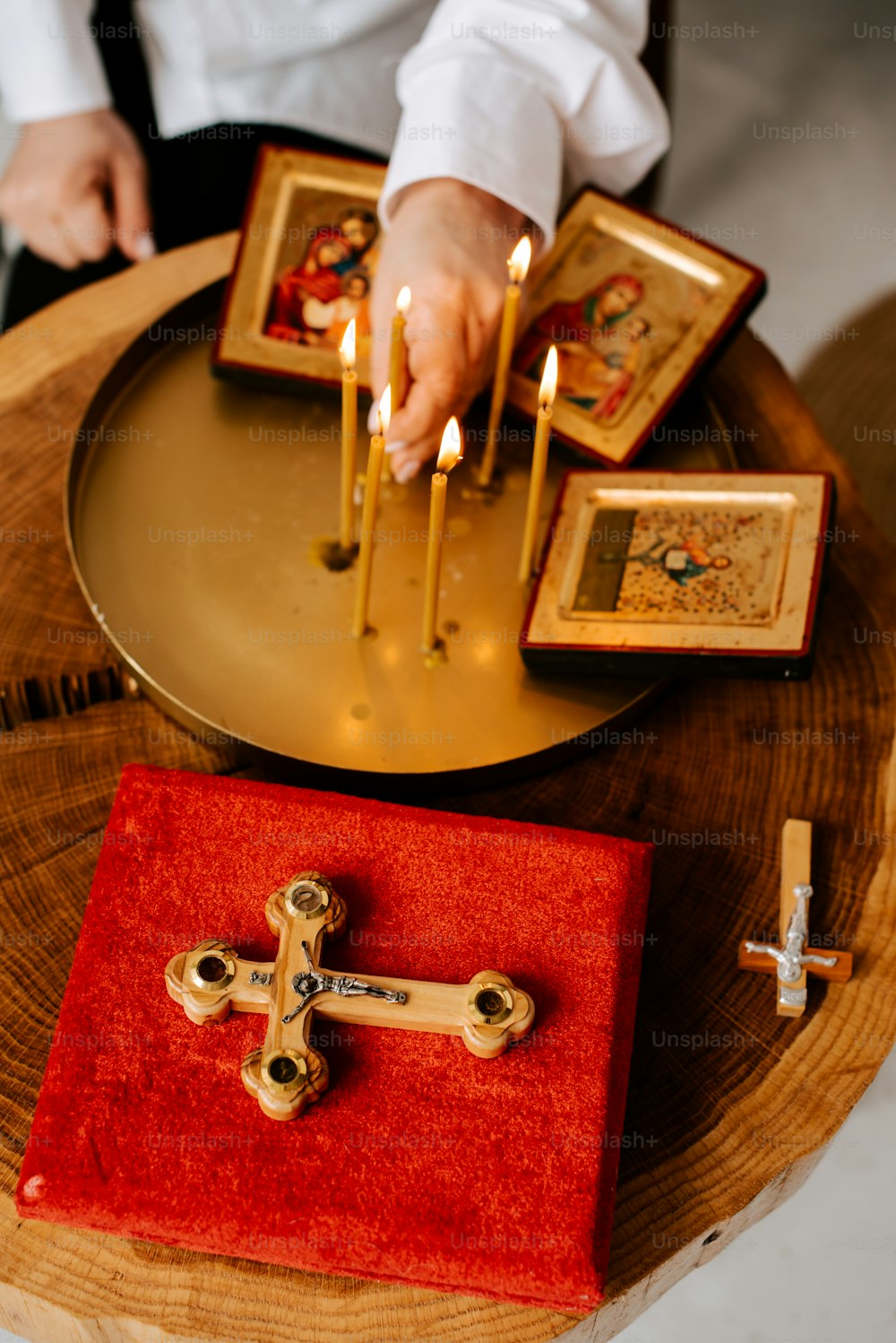 eine Person, die Kerzen an einem Kreuz auf einem Tisch anzündet