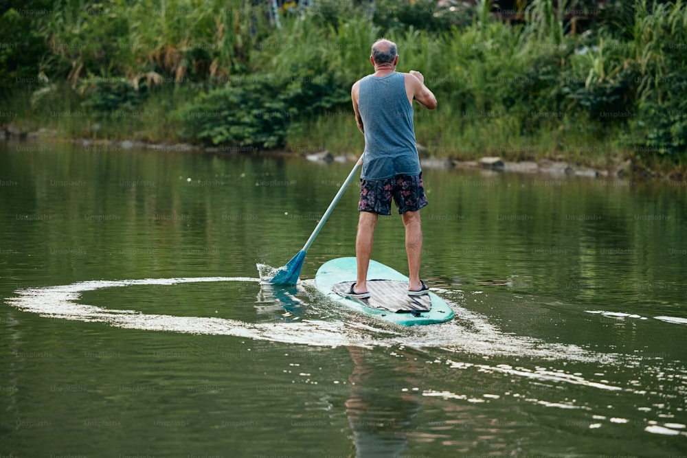 Ein Mann, der auf einem Paddelbrett auf einem Fluss paddelt