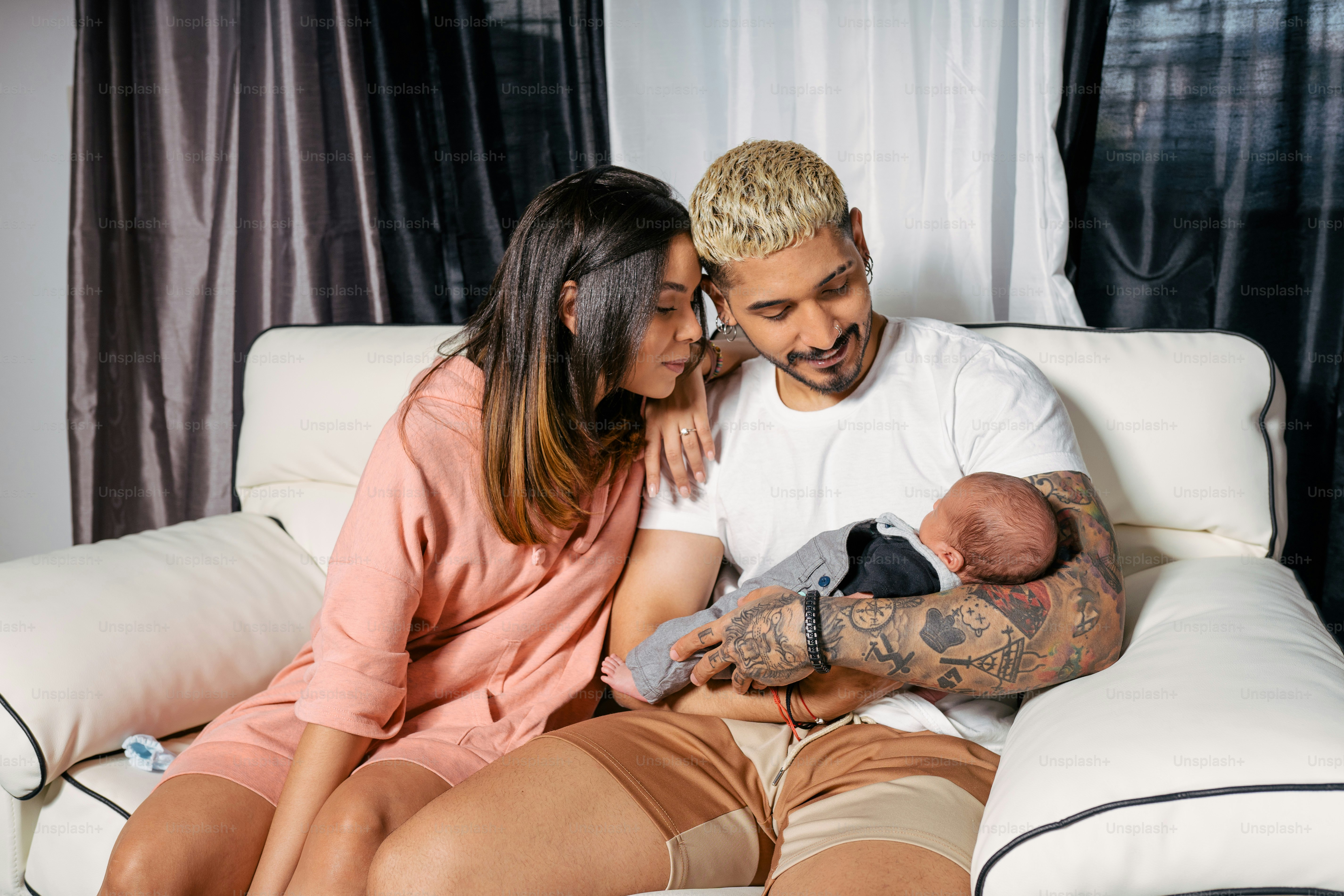 a man and woman sitting on a couch holding a baby
