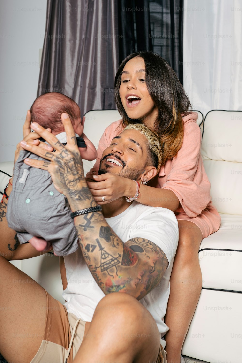 a man holding a baby and a woman sitting on a couch