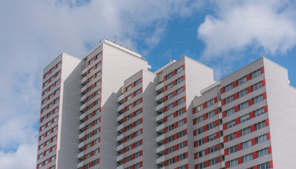 a tall white building with red windows under a cloudy blue sky