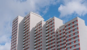 a tall white building with red windows under a cloudy blue sky