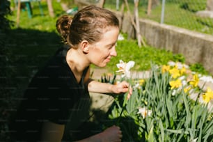 庭で花の匂いを嗅ぐ女性