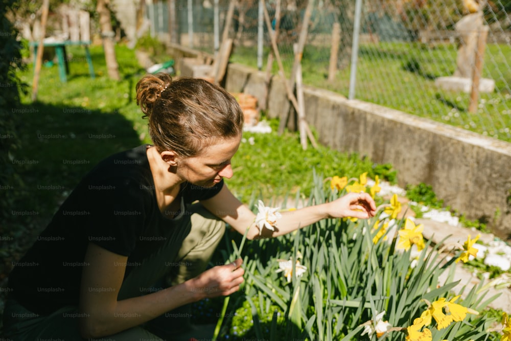 a woman kneeling down next to a garden filled with flowers