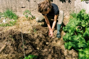 une personne agenouillée dans la terre près d’un jardin