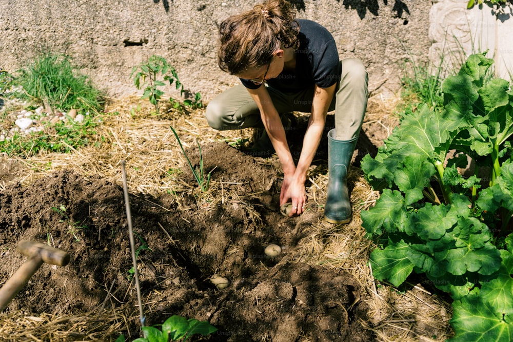 a person kneeling down in the dirt near a garden