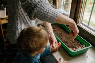 女性が子供が植物を植えるのを手伝っている