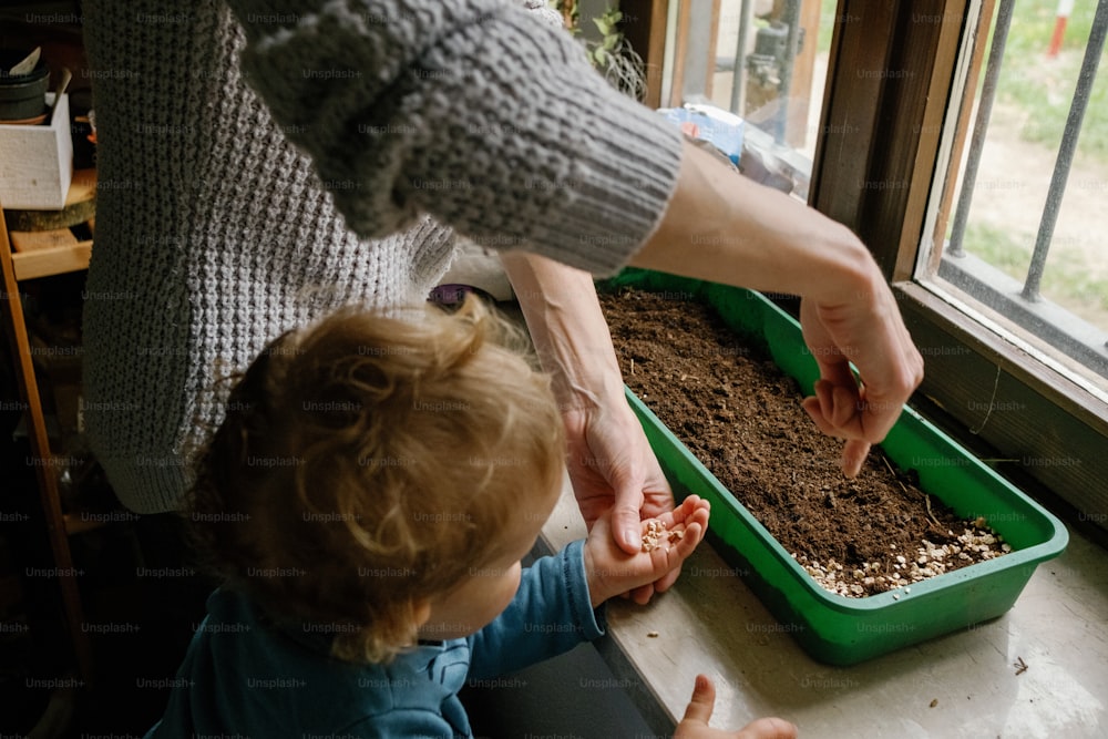 a woman is helping a child to plant a plant