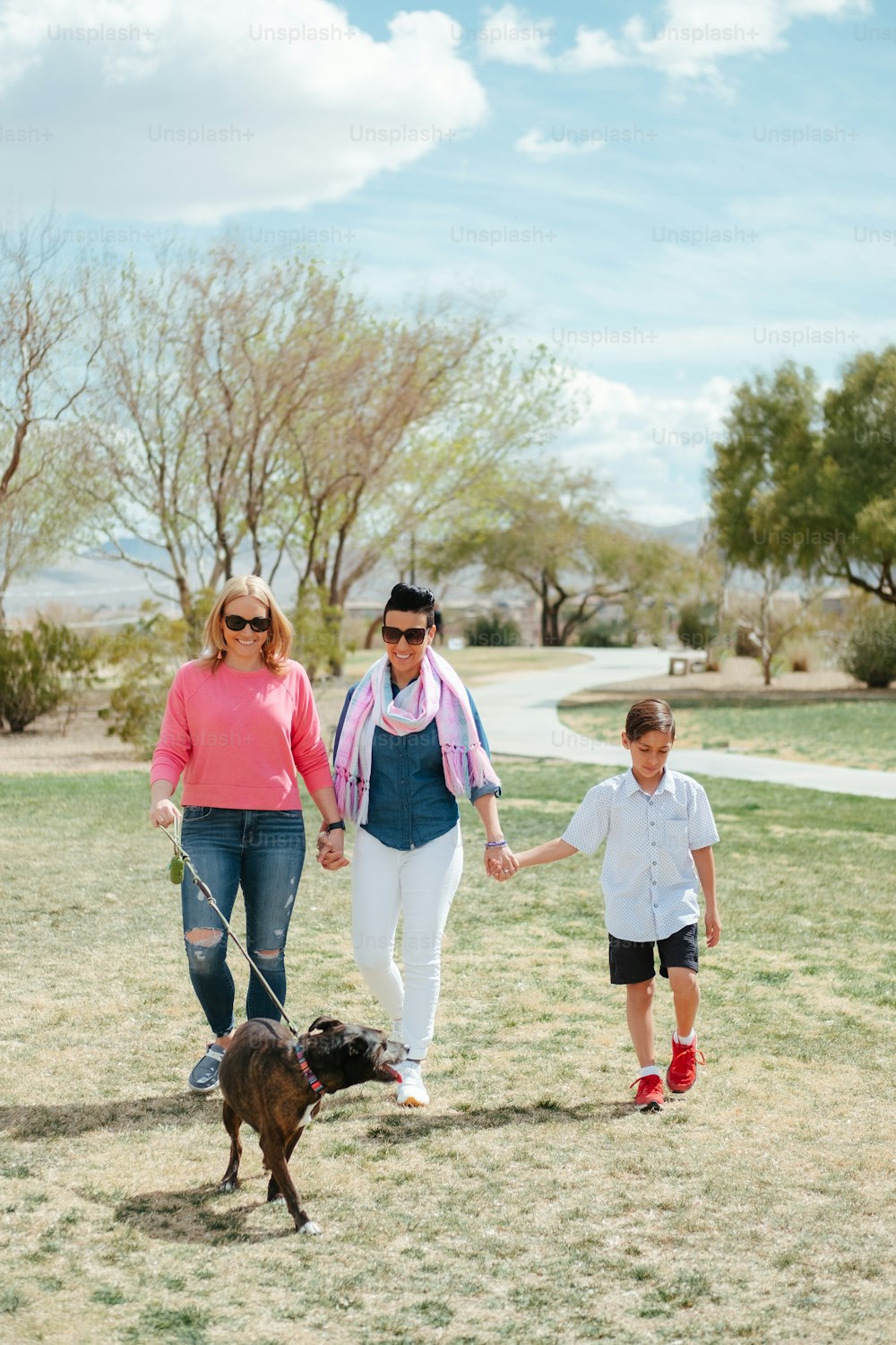 eine Frau und zwei Kinder, die mit einem Hund spazieren gehen