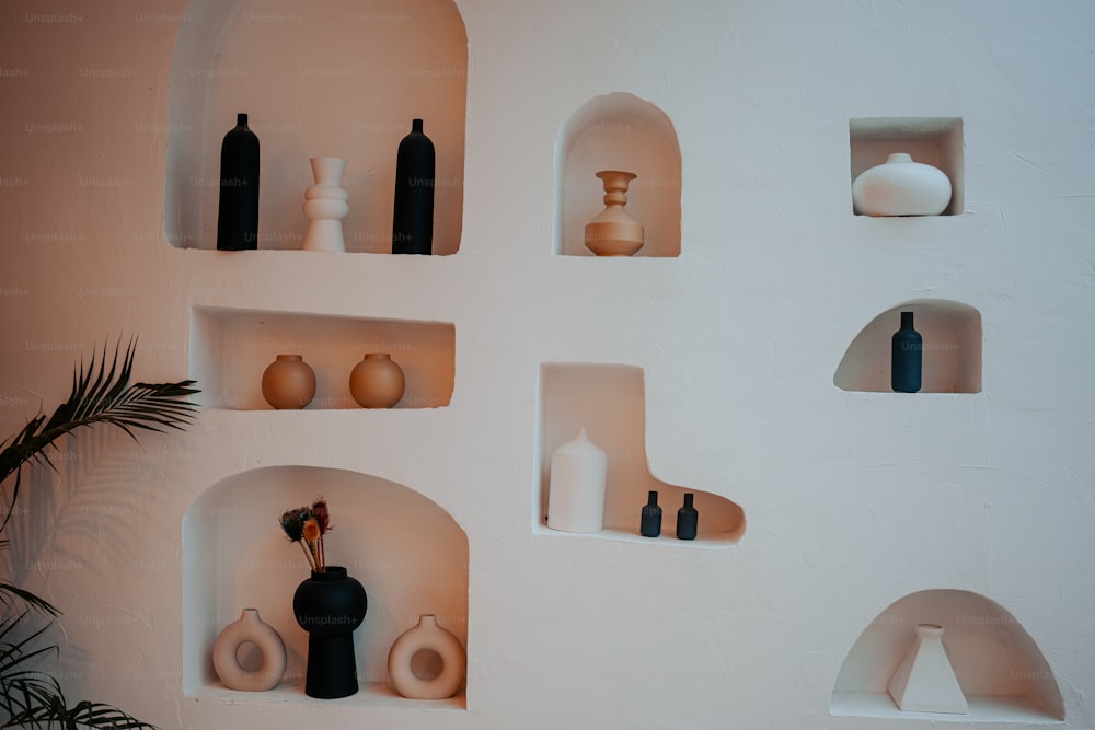 una parete bianca piena di scaffali pieni di vasi