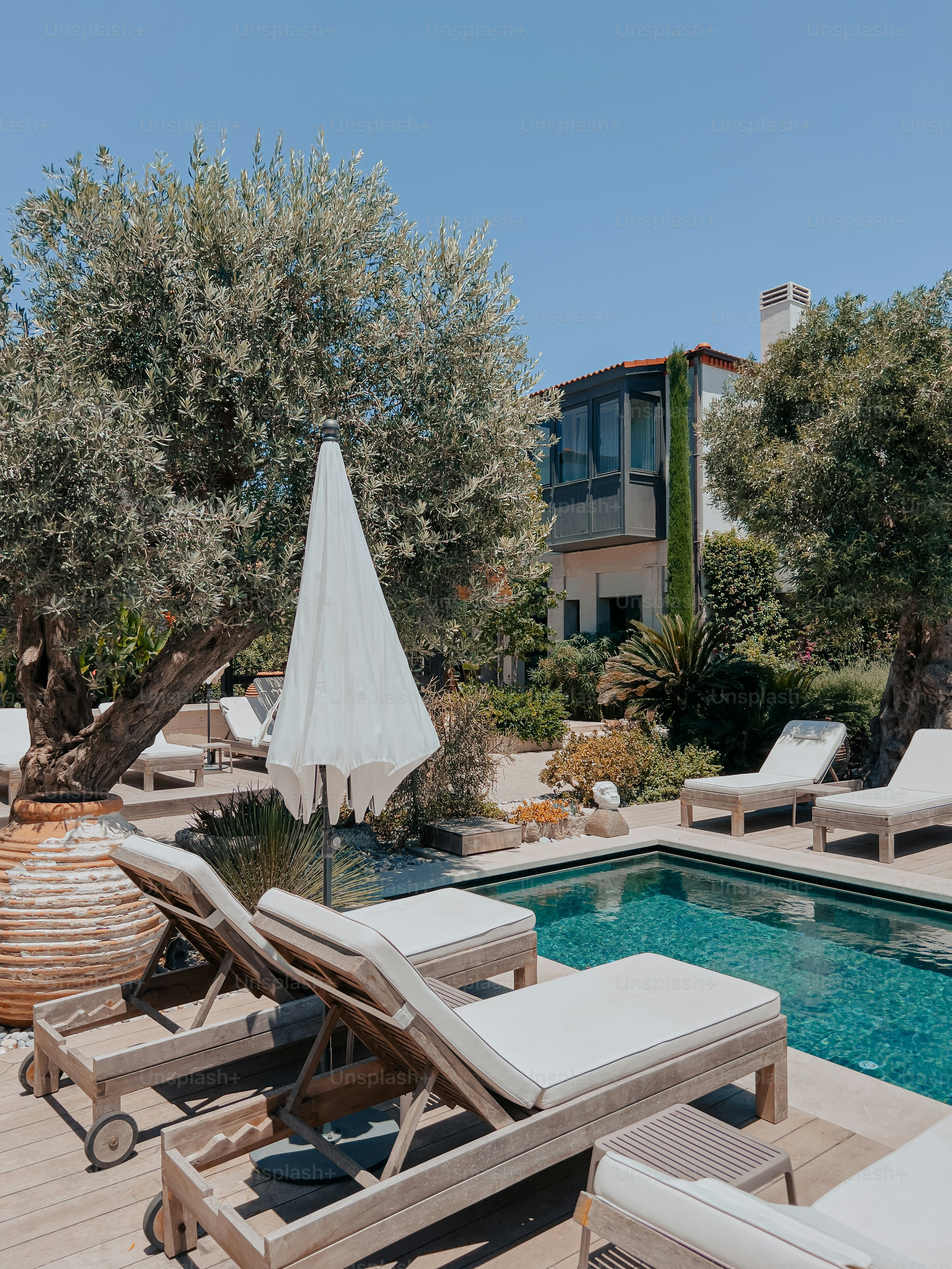 A pool with lounge chairs and an umbrella photo – Summer Image on Unsplash