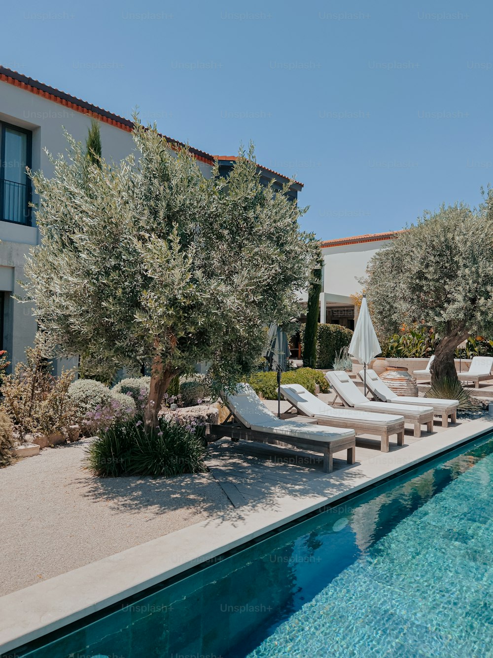 a pool with lounge chairs and an umbrella next to it