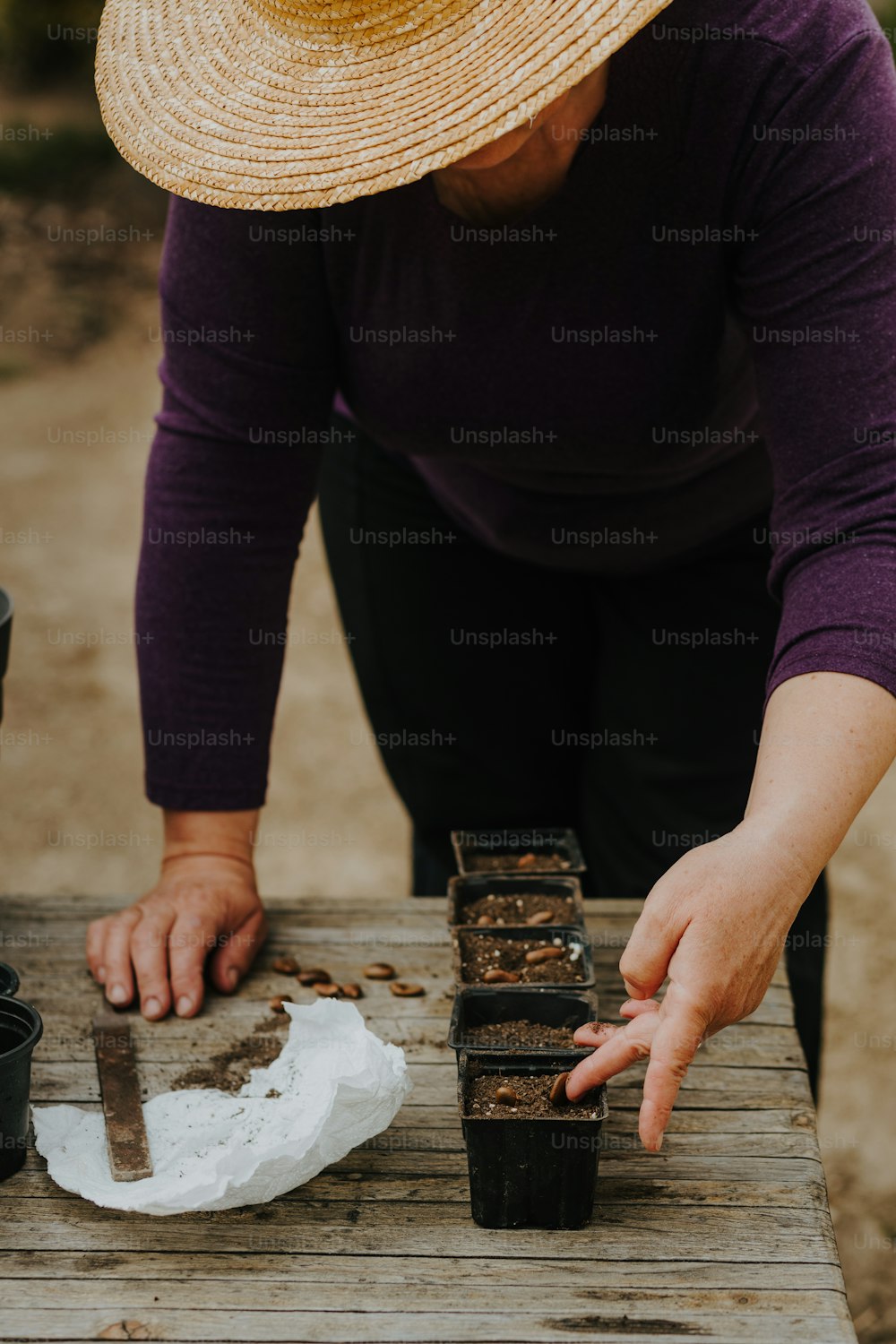 a woman in a straw hat picking up a piece of cake