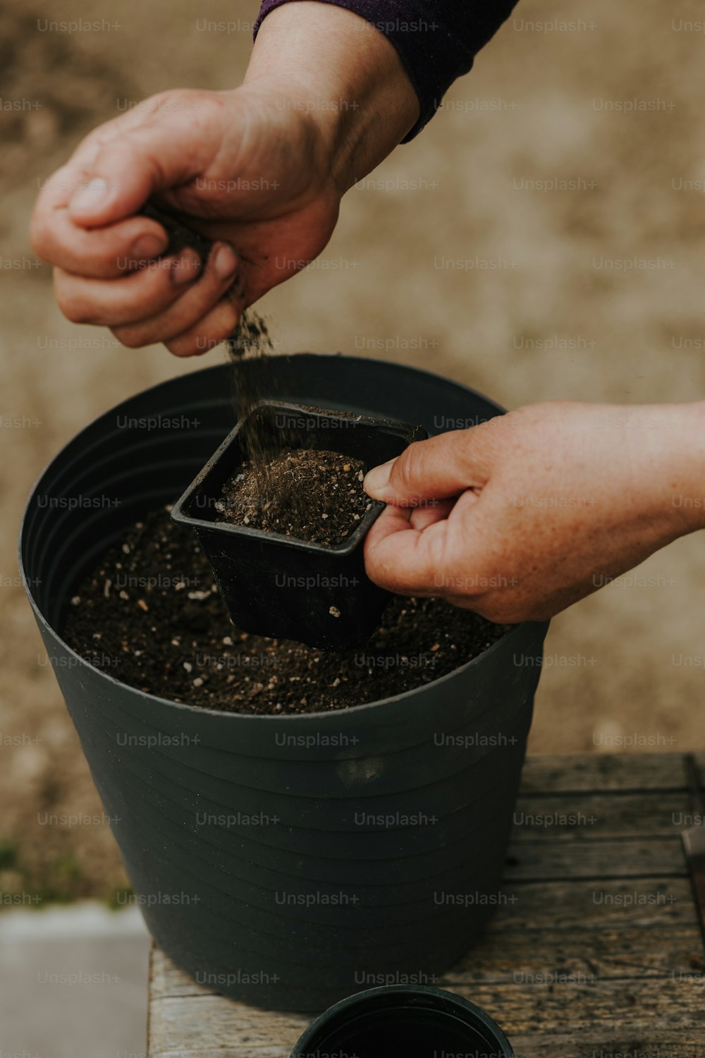 une personne ramassant de la terre dans une plante en pot
