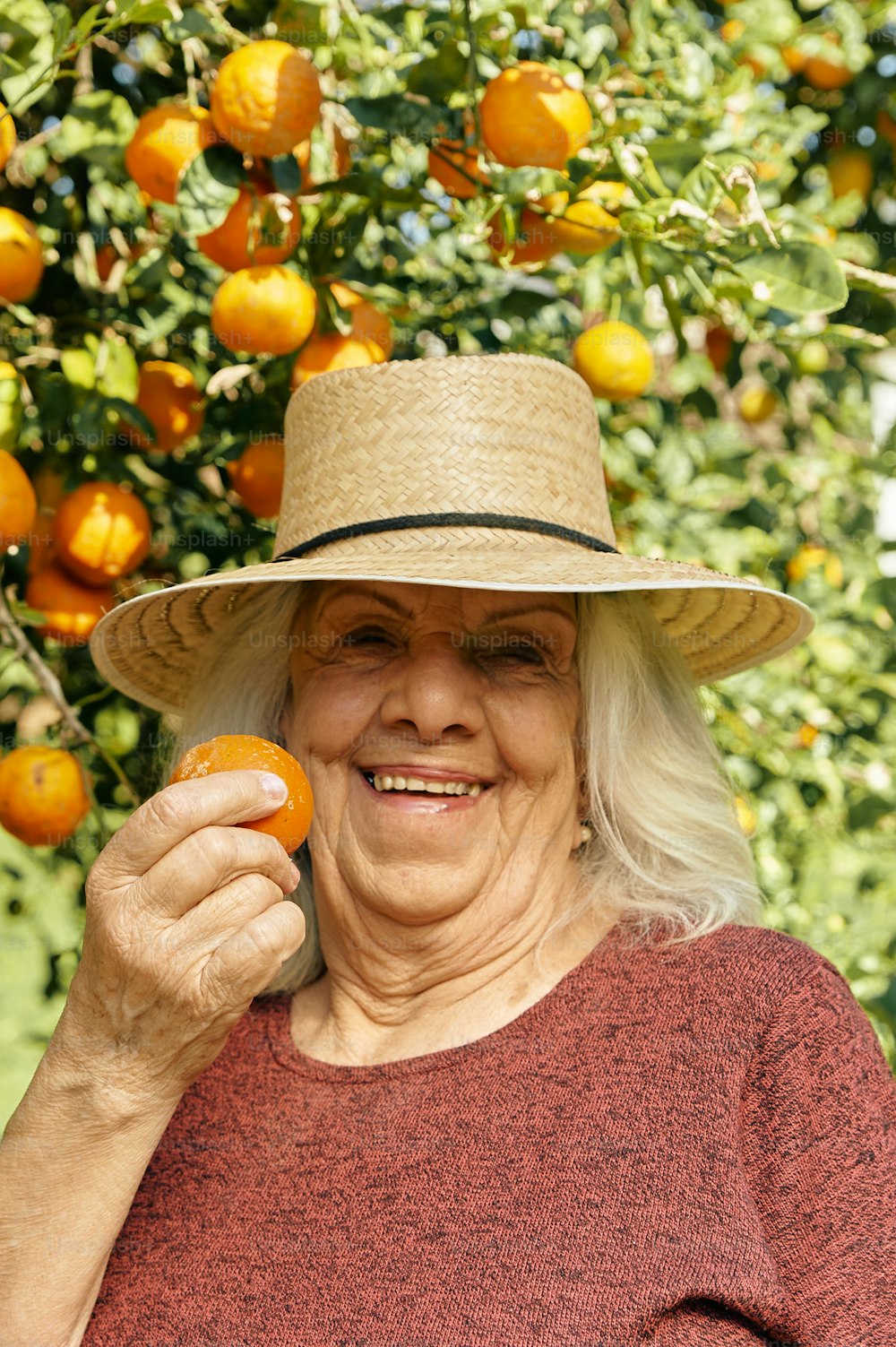 uma mulher em um chapéu de palha segurando uma laranja