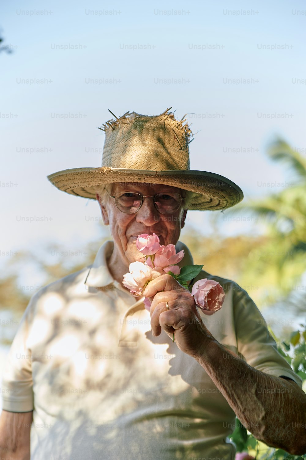 ein Mann, der einen Strohhut trägt und eine Blume hält