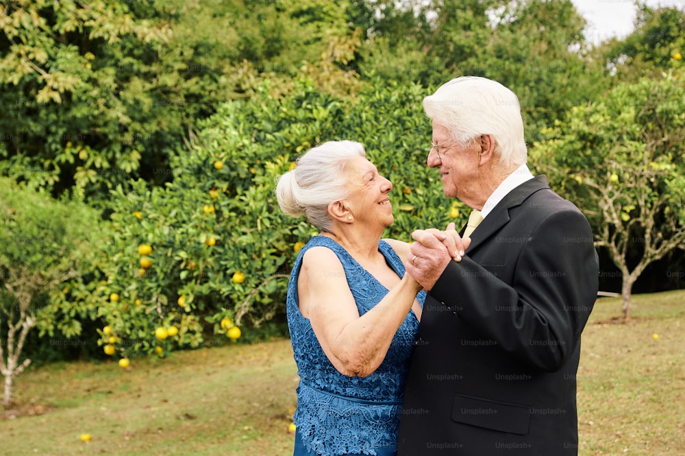 an older couple dancing together in front of trees