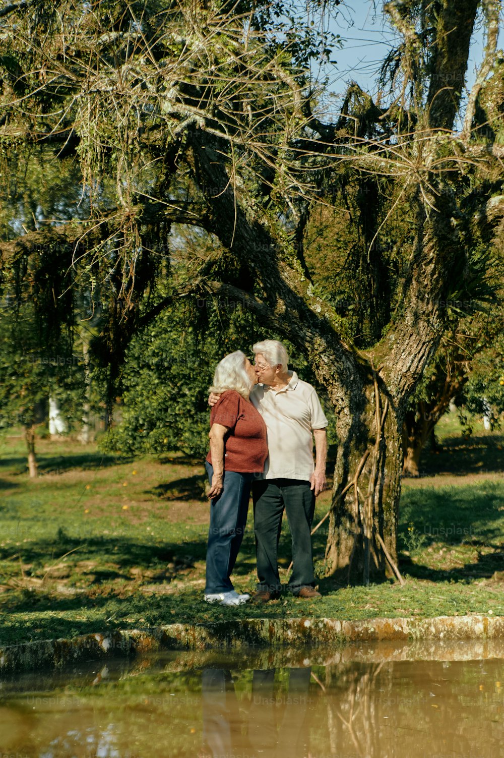 um par de pessoas de pé ao lado de uma árvore