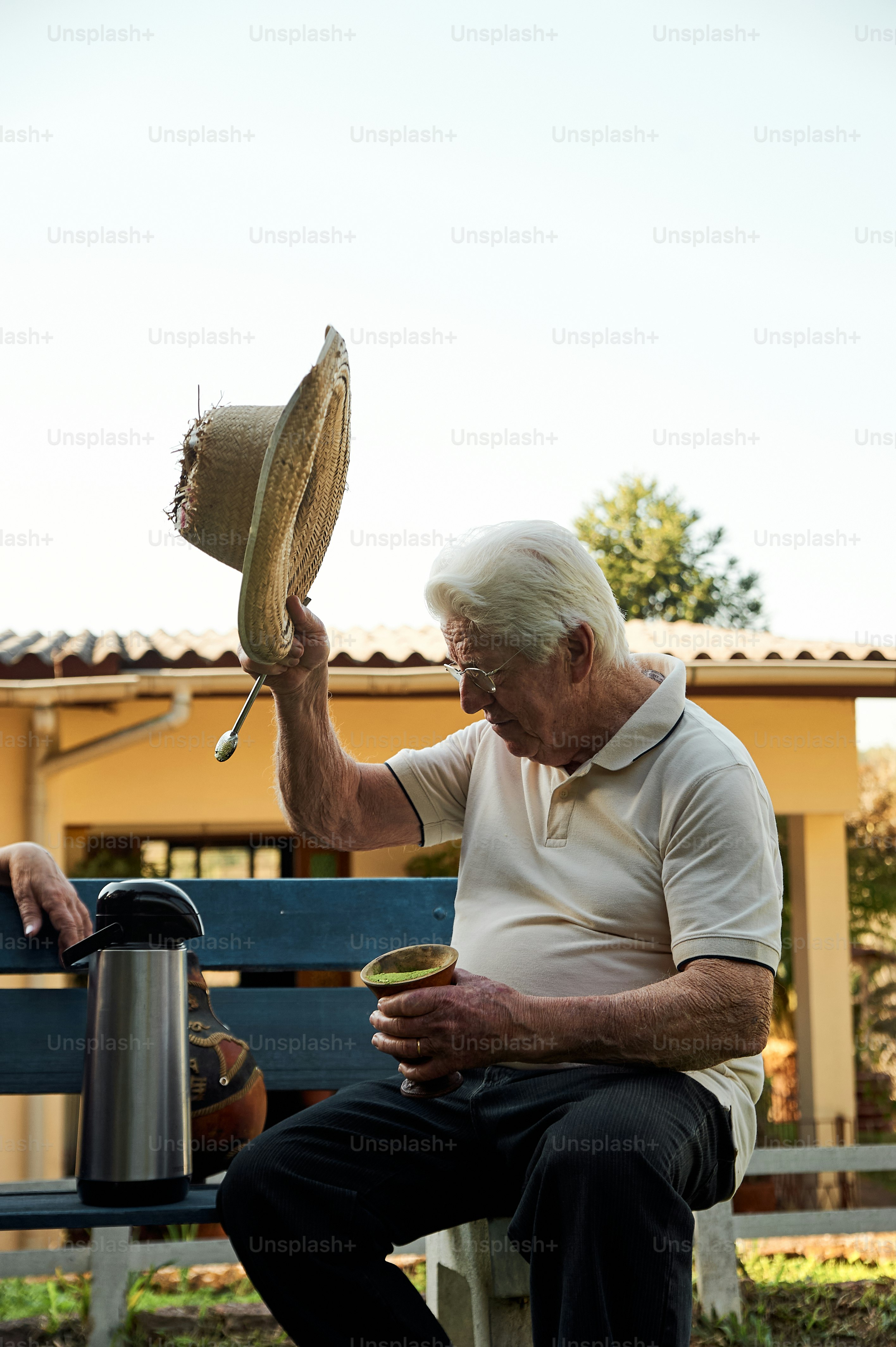 a man sitting on a bench holding a hat