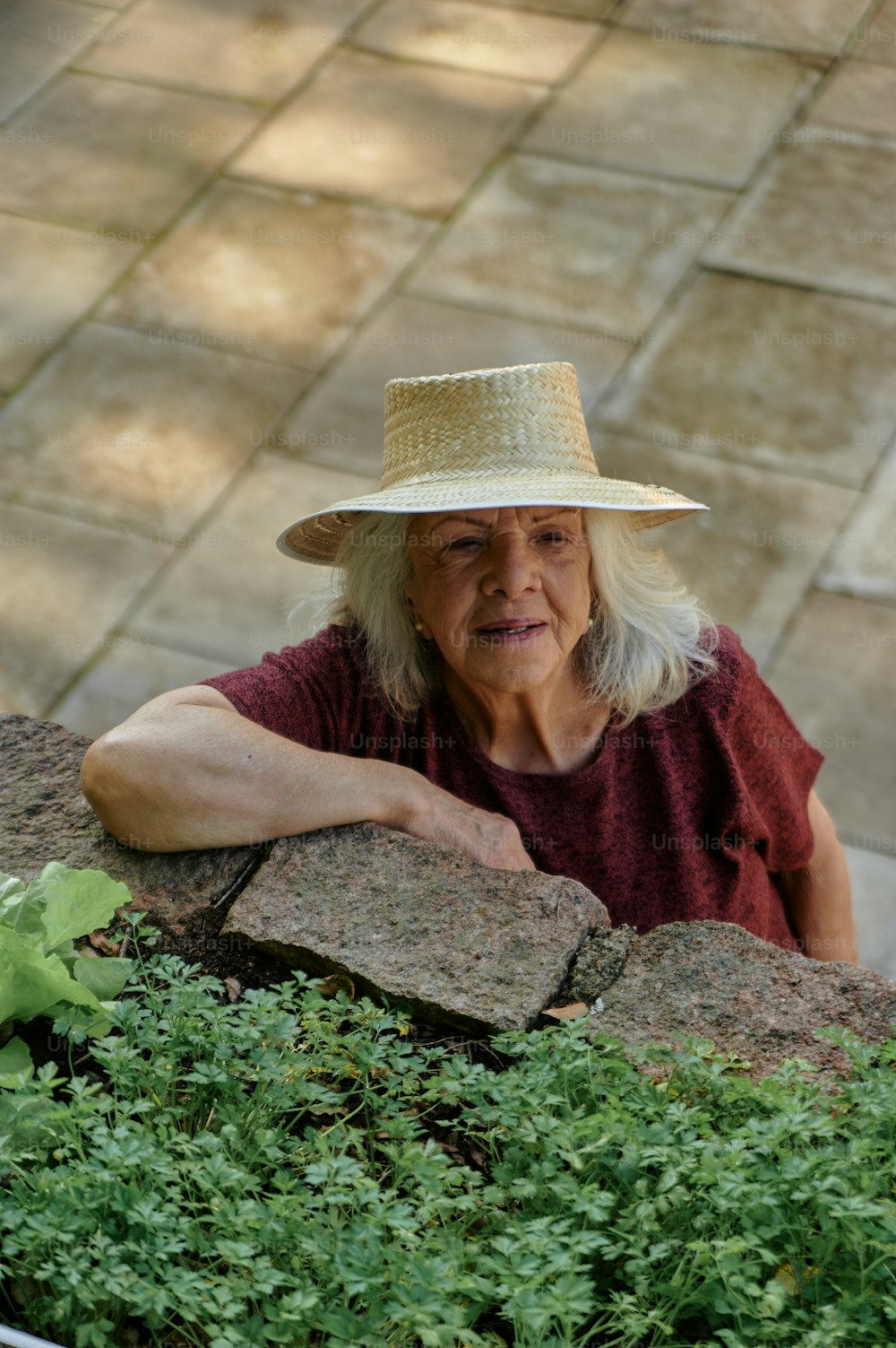 a woman wearing a straw hat leaning against a wall
