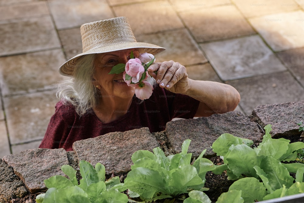Una mujer con un sombrero de paja oliendo una flor