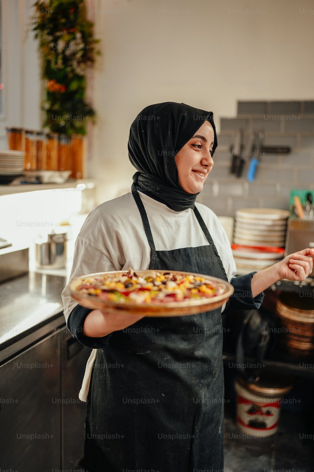 a woman in an apron holding a pizza