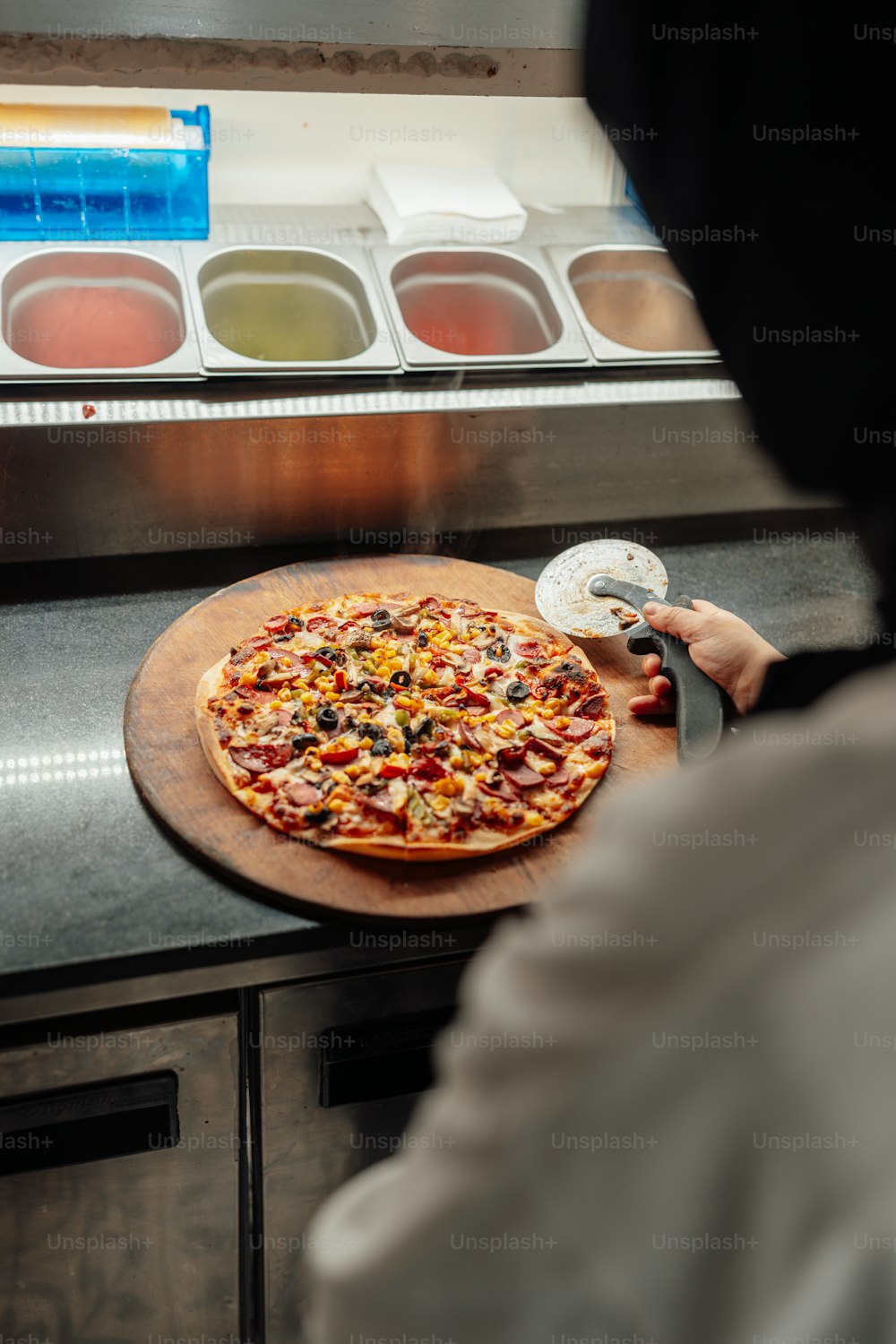 a person cutting a pizza with a pizza cutter