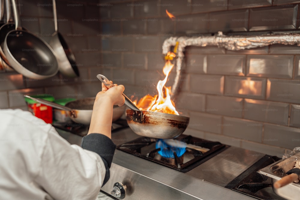 uma pessoa cozinhando comida em um wok em um fogão